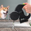 Black dual retractable leash held beside a dog